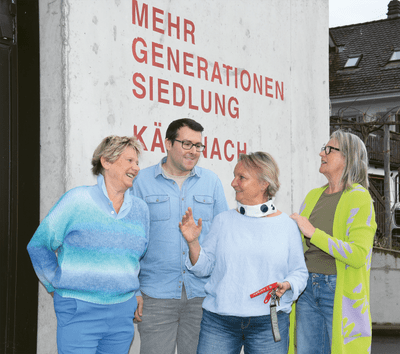 Vier Personen stehen vor einer Wand mit rotem Text.