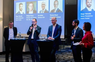 Podiumsdiskussion mit fünf Personen vor Projektionsbildschirm.
