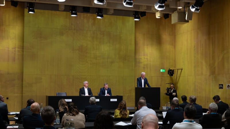 Menschen in einem Konferenzsaal, Redner am Podium, Publikum zuhört.